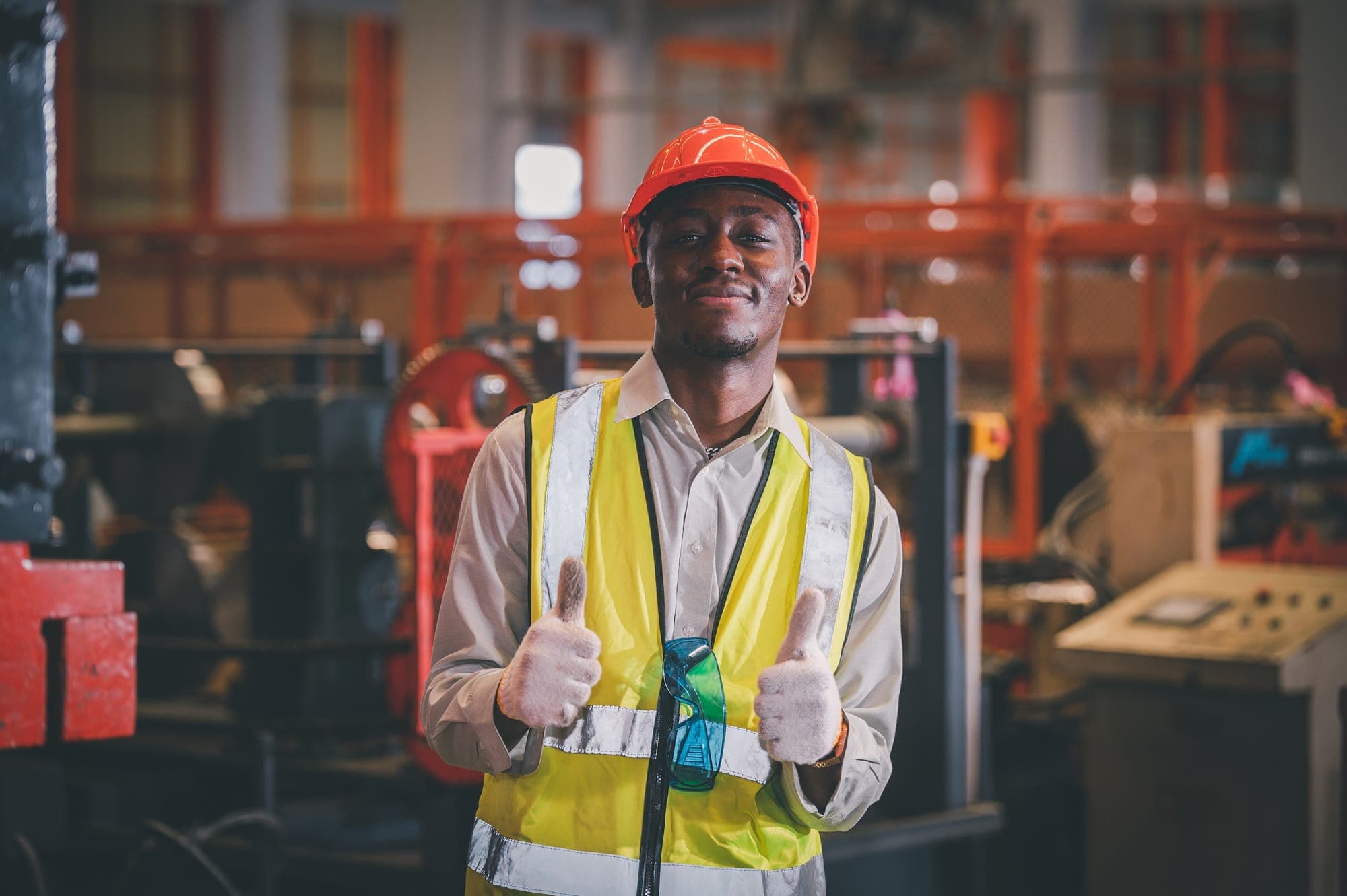 A factory worker in safety gear giving a thumbs up